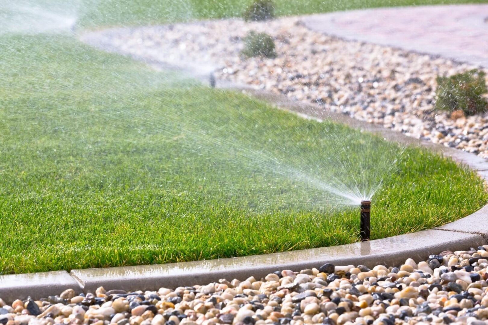 A lawn with grass and water sprinklers on it.